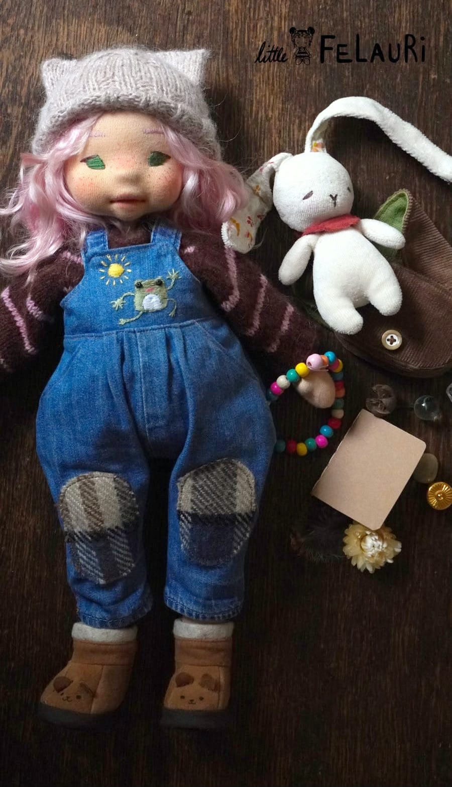 Natural fibre art doll with pink hair, wearing dungarees and a cat-eared hat and with a toy rabbit, all made by Mari of Little Felauri.