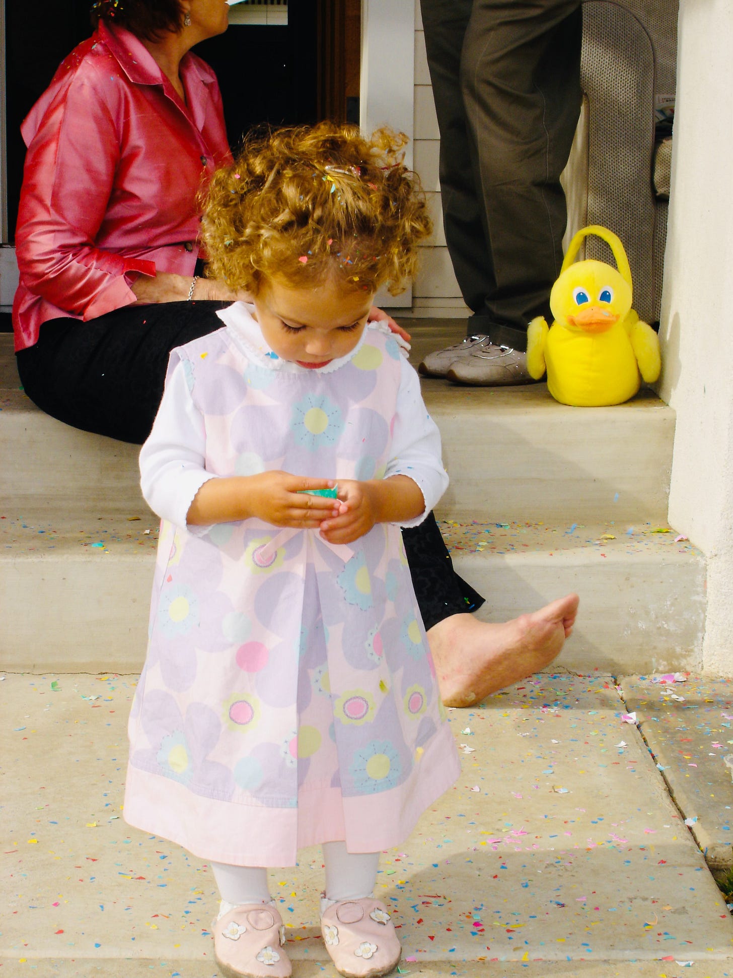 A little girl in an Easter dress standing in confetti on the front steps with a rubber duck basket — Easter tradition at The Dinner Bell Hearth