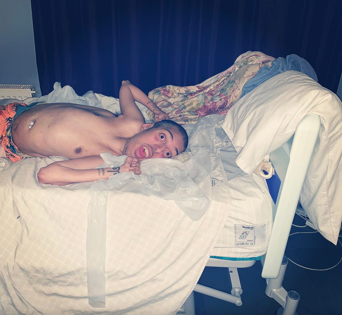 A shirtless Sulaiman lying in bed. 