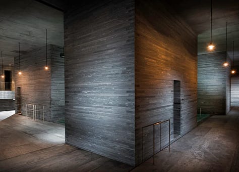 Interior of Therme Vals thermal baths by Peter Zumthor, Vals, Switzerland. Dark quartzite stone walls and thermal water pools lit by natural light from above. Architecture by Peter Zumthor.