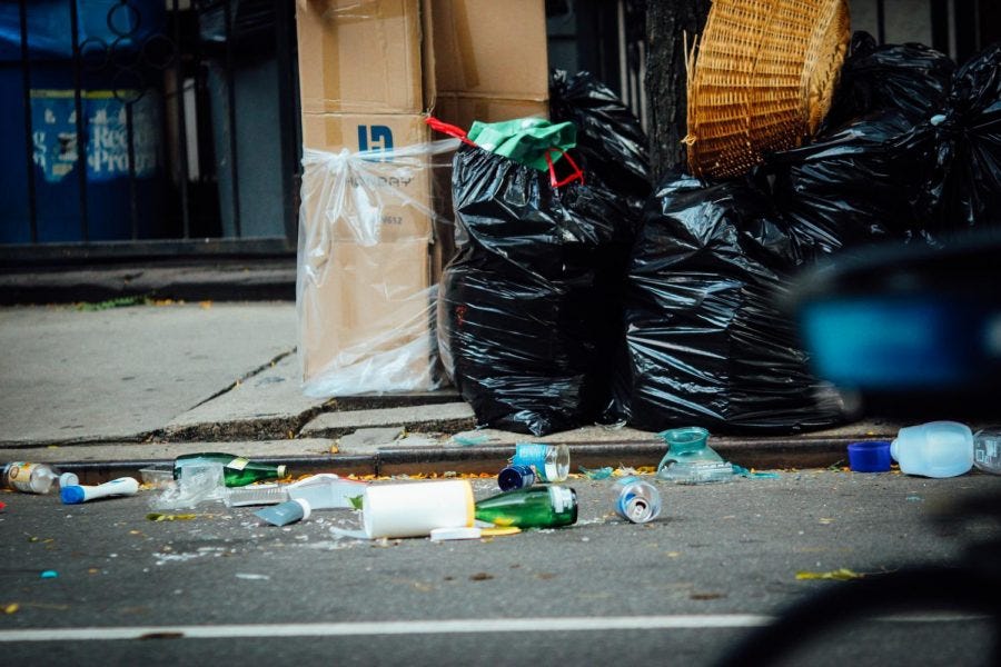 Black+garbage+bags+on+sidewalk+with+trash+around+it