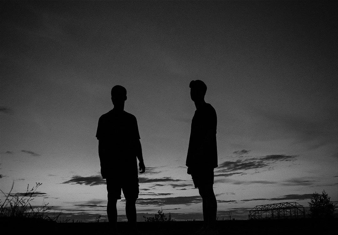 silhouette of couple standing on seashore during sunset silhouette of couple standing on seashore during sunset