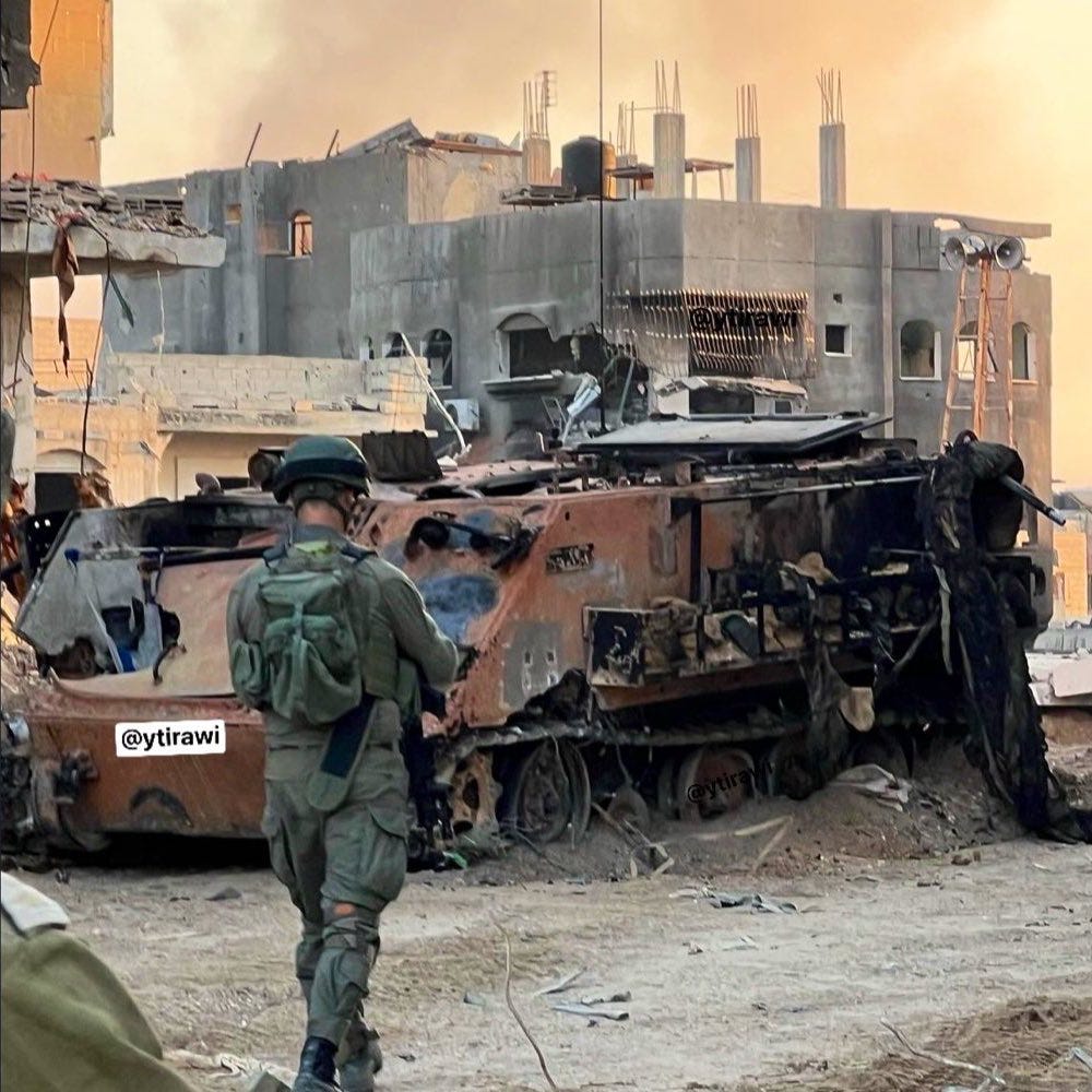 After proximity meets armor: a destroyed Israeli tank smolders as an IDF soldier surveys the damage—evidence of how close-quarters resistance can halt even the most advanced machinery.