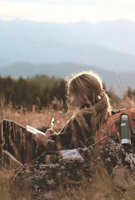 This may contain: a woman sitting on top of a grass covered field