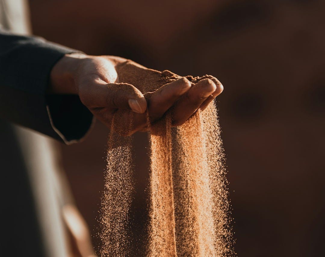 a person holding sand in their hands
