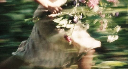 This may contain: a blurry photo of a woman holding flowers