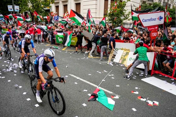 Riders of the Israel-Premier Tech team compete as people holding Palestinian flags try to disrupt the 11th stage of the Spanish Vuelta cycling race in Spain