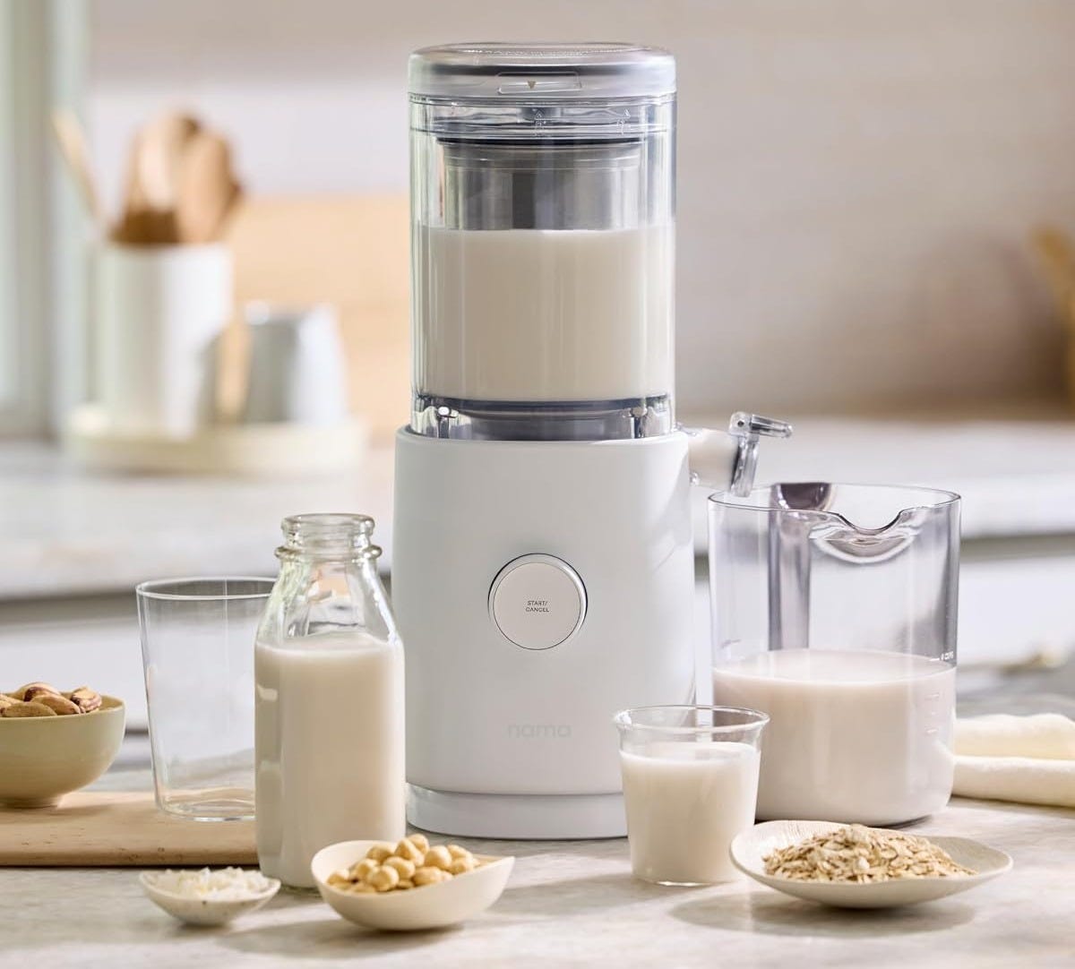  a white Nama M1 Plant Milk Maker on table with glasses filled with milk
