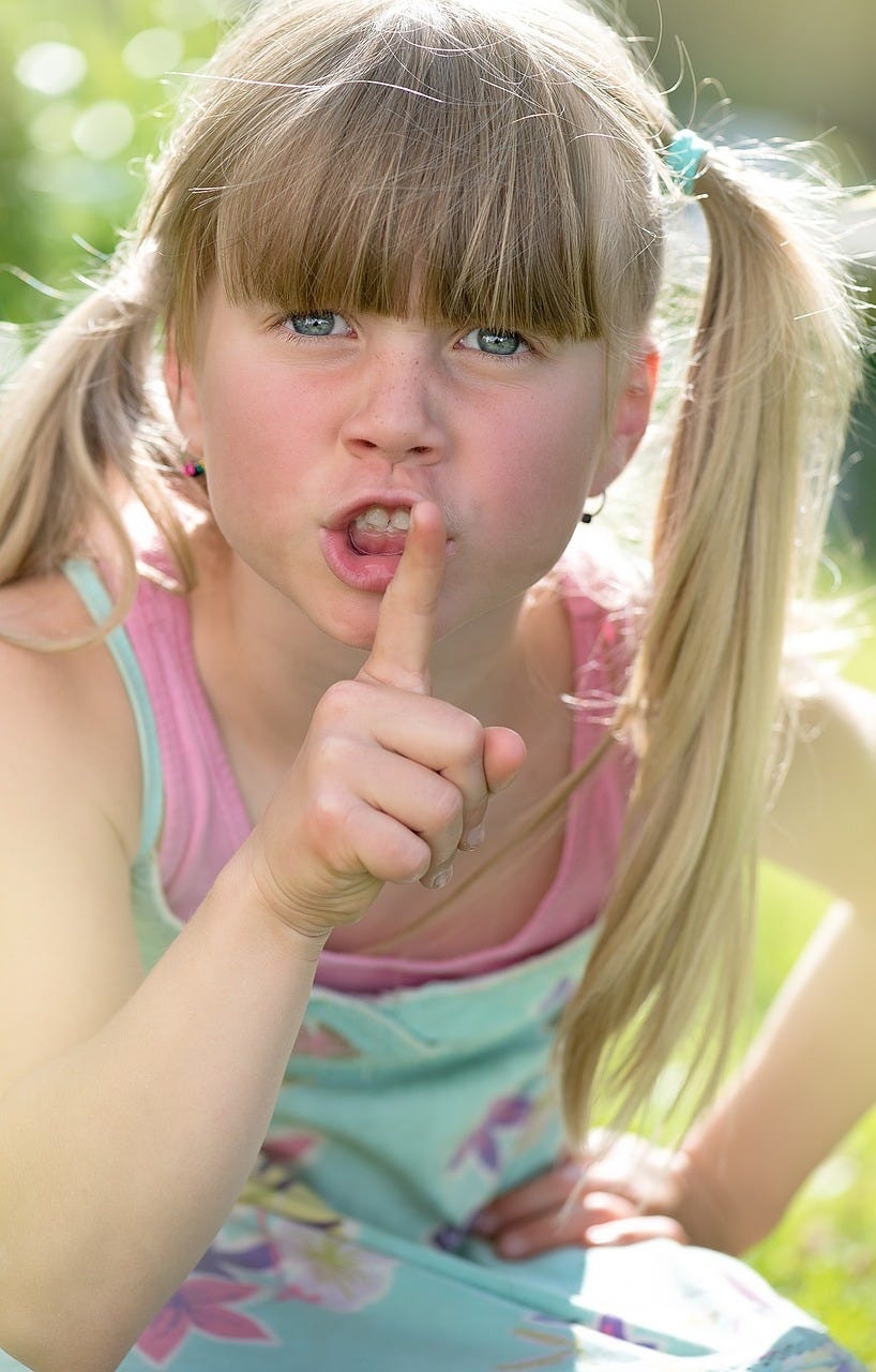 close up image of a girl with pigtails shushing 
