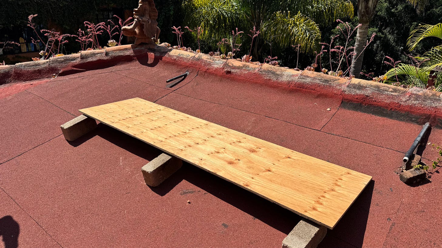 A wooden board on a roof propped up with three concrete blocks.