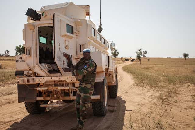 Man in military uniform outside an armoured vehicle on a road Man in military uniform outside an armoured vehicle on a road