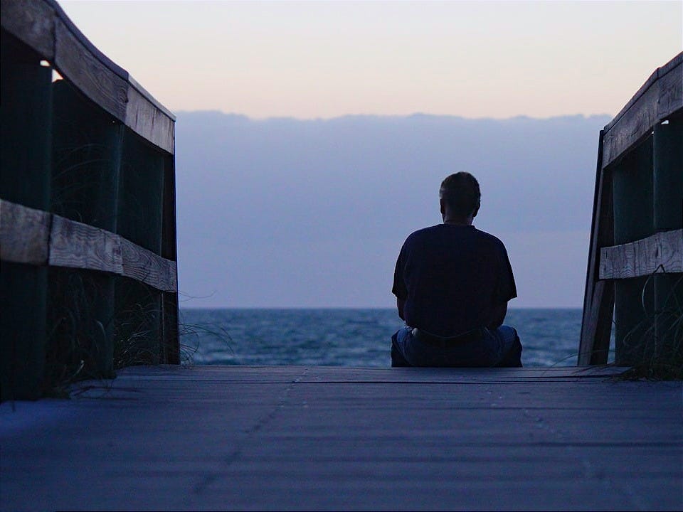 a person sitting on a dock looking out at the water