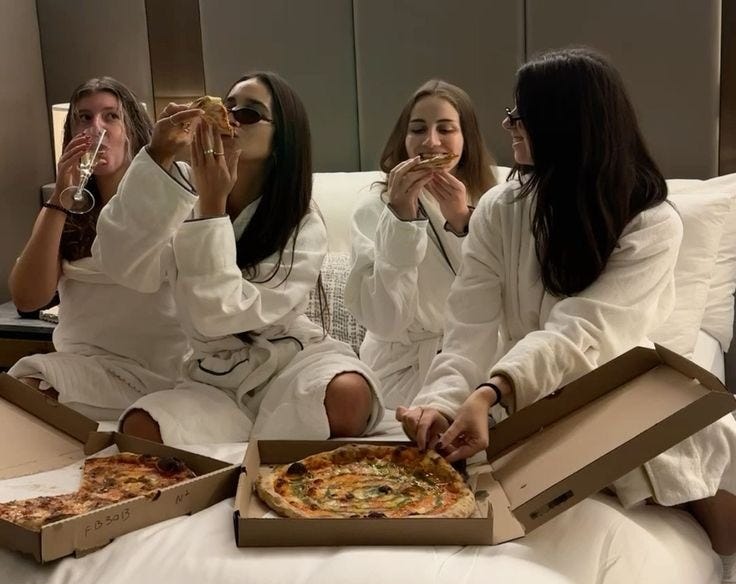 This may contain: four people sitting on a bed eating pizza and drinking water