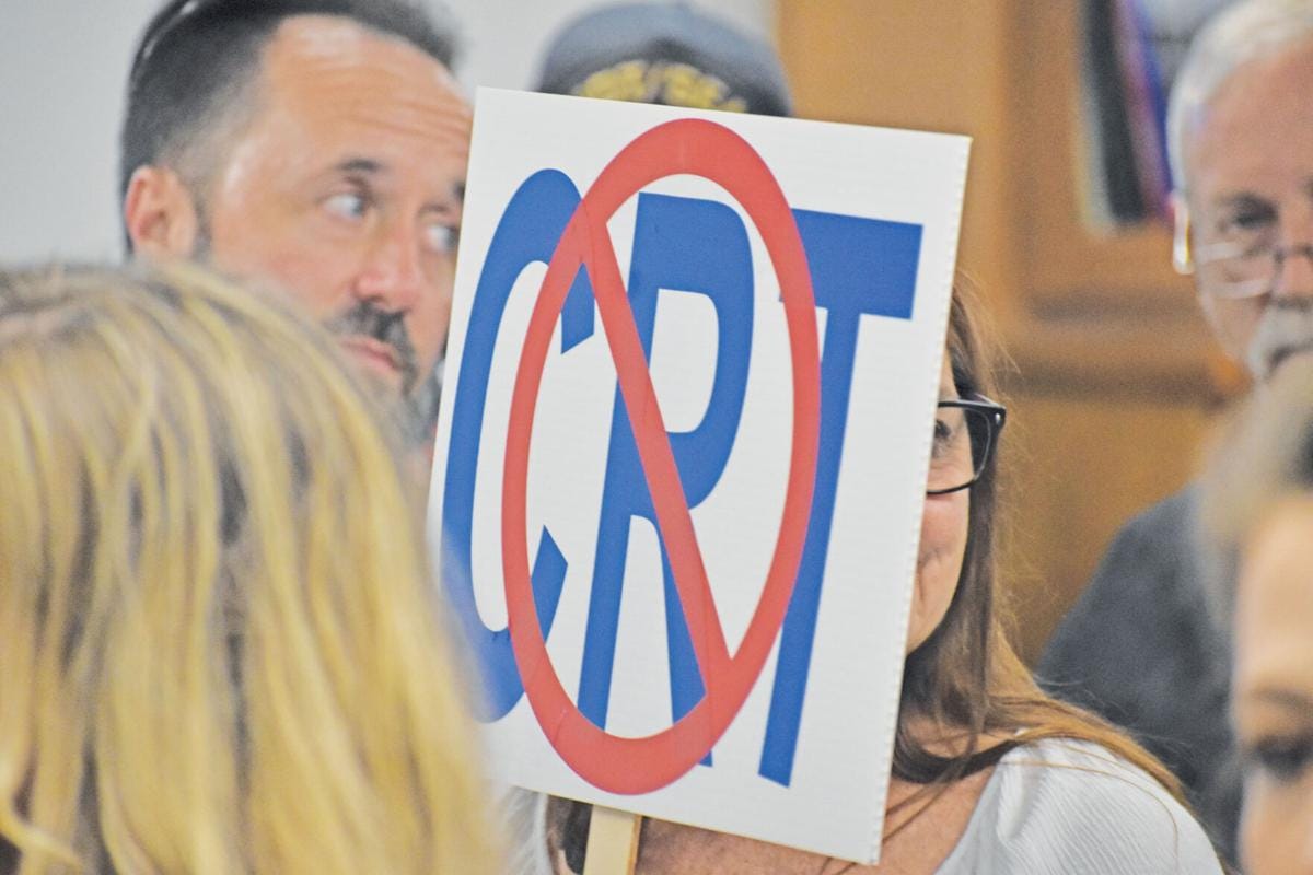 White man holding sign that says "no critical race theory"