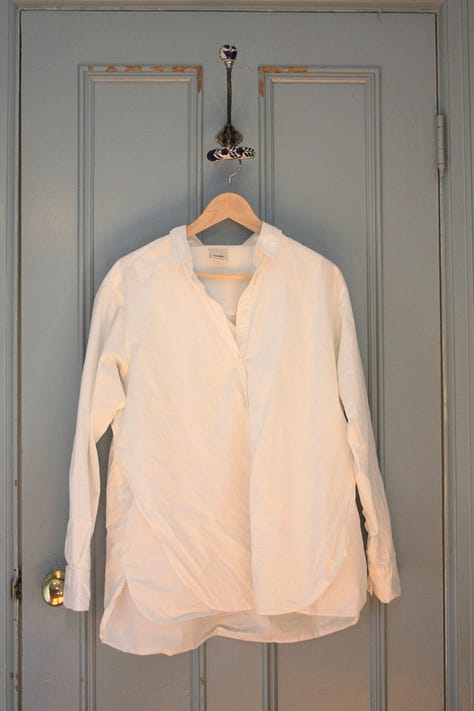 Five shirts, from left to right a white shirt, green turtleneck, oatmeal turtleneck, white t-shirt, and brown turtleneck