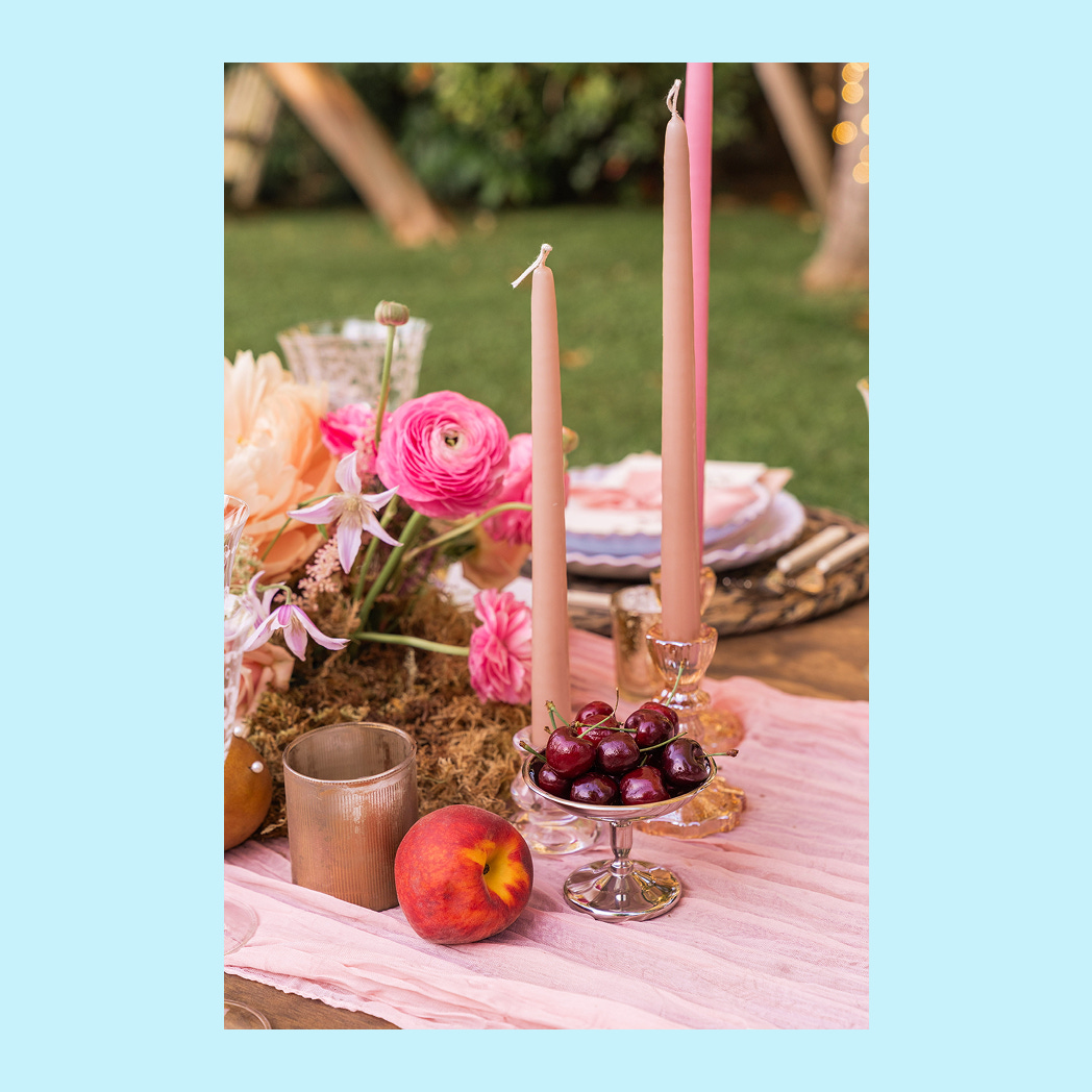 A table with a layered centerpiece showing candles and coup glasses at different heights.