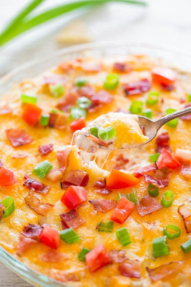 A spoon lifting a scoop of Loaded Baked BLT Dip from a bowl. A spoon lifting a scoop of Loaded Baked BLT Dip from a bowl.