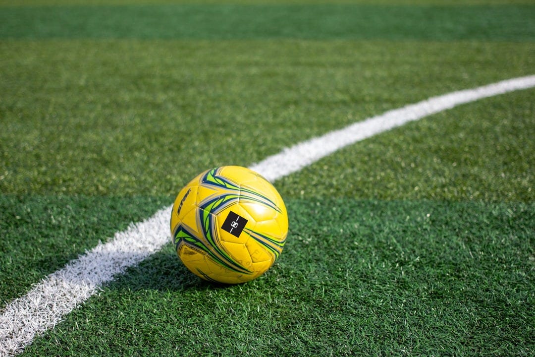 A yellow soccer ball rests on the green field.