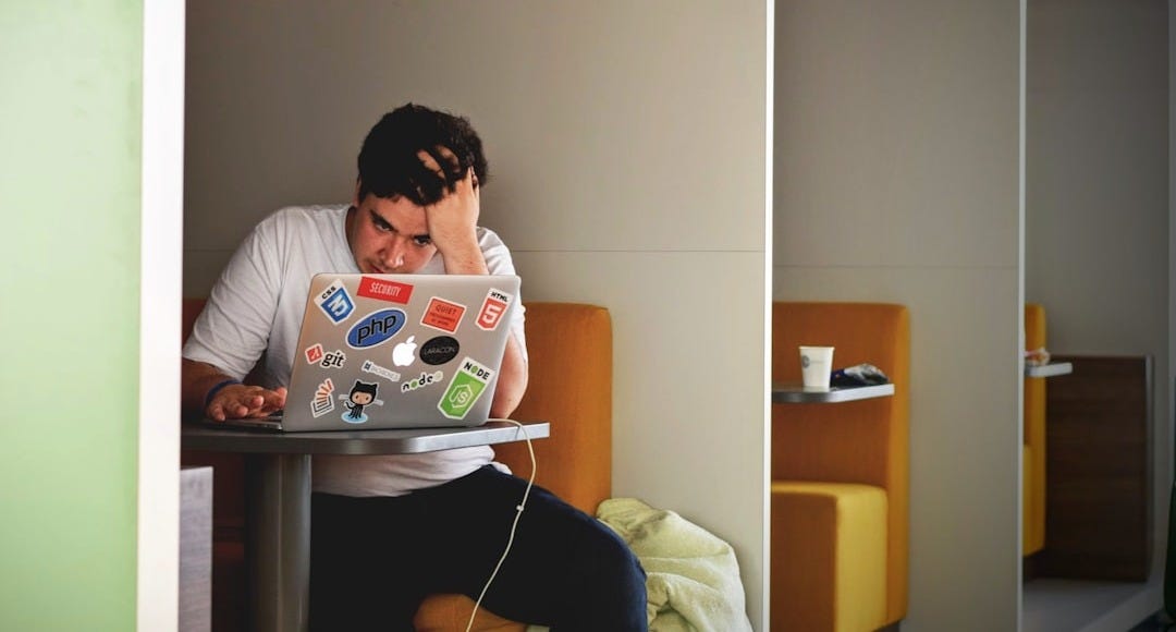 man wearing white top using MacBook