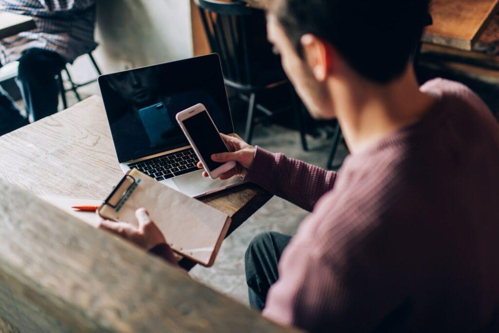 millennial IT professional with textbook checking received email on cellular millennial IT professional with textbook checking received email on cellular