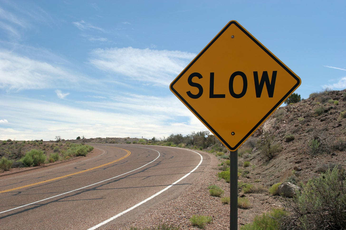 A tight curve on a roadway and a sign reading "SLOW"