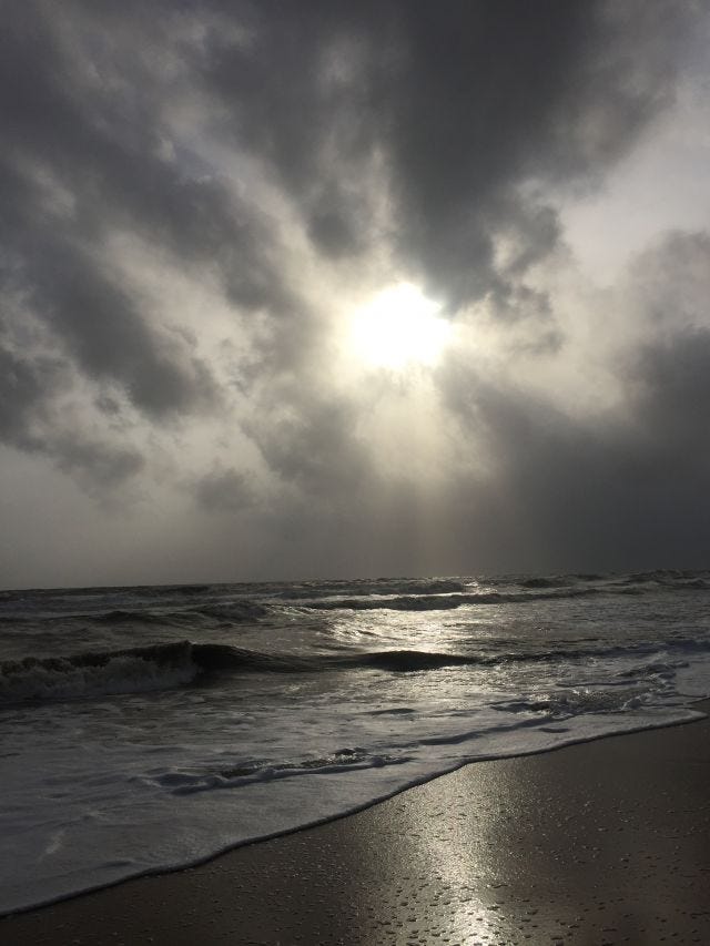 The sun in the sky over the waters of a sea - colours of the sky seem dark The sun in the sky over the waters of a sea - colours of the sky seem dark