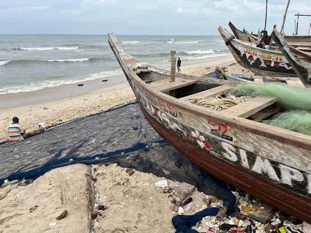 A fisherman sits on the sand at the beach to fix his net