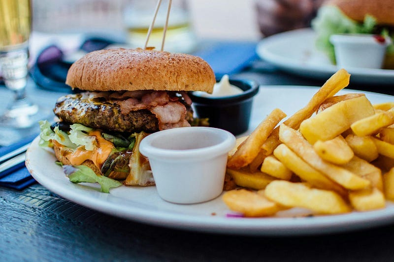 A Plate of a burger, french fries and sauces.