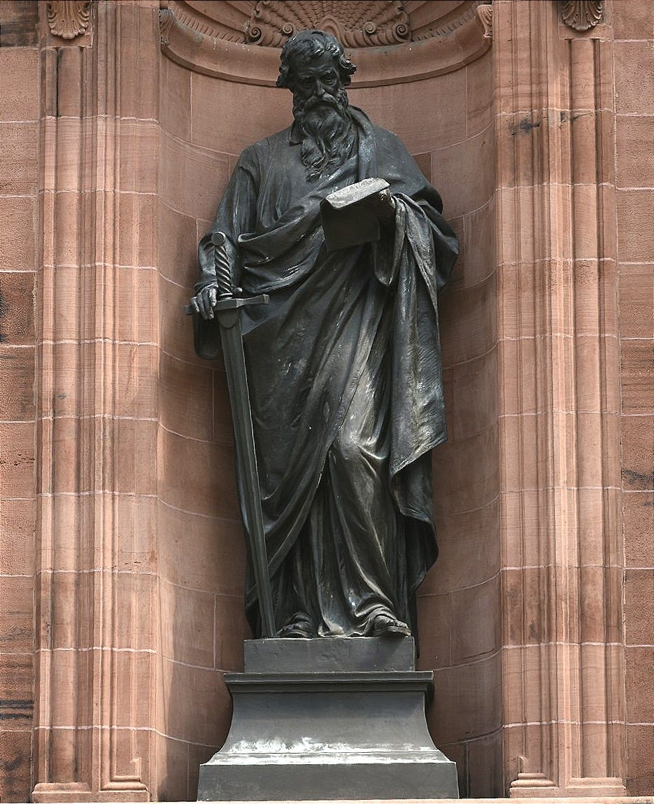 a statue of a man holding a book in front of a building