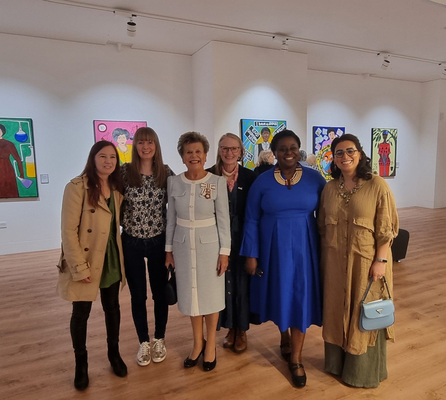 A group of 6 women posing in a gallery 