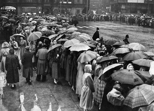 Manchester crowds seek protection from the rain under their umbrellas whilst waiting for
