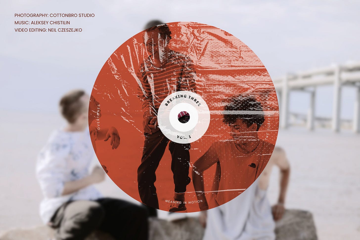 Cover image featuring a textured compact disc graphic tinted terracotta red with the text "Breaking Three, Vol. 1." The disc overlays a desaturated photograph of three teenage boys talking animatedly with the sea behind them. In the upper-left corner, the metadata text reads: "PHOTOGRAPHY: cottonbro studio, MUSIC: Aleksey Chistilin, VIDEO EDITING: Neil Czeszejko." Part of the Overtones series at The Subtext Review.
