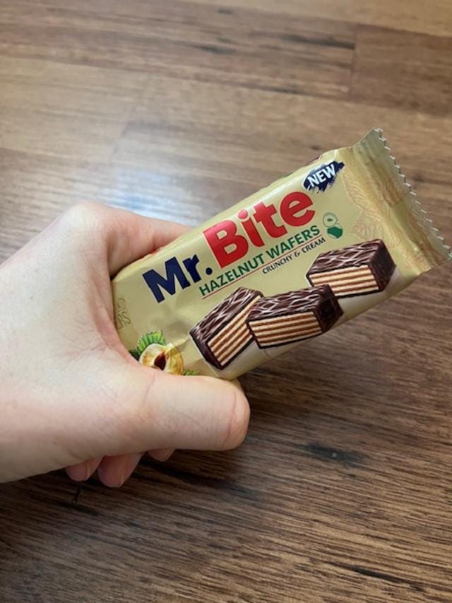 OP's clenched hand holding a wrapped candy bar called "MR. BITE" with an image of the chocolate-coated cross-section of layered wafers and hazelnut creme.