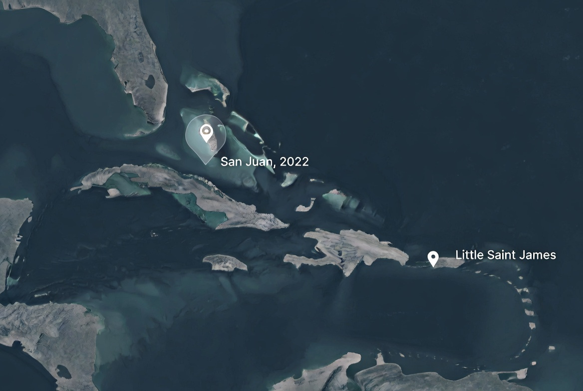 A dark overhead map illustration of the Caribbean showing two marked locations — San Juan Puerto Rico and the U.S. Virgin Islands — connected by a dashed line across open water.
