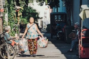 senior woman walking with two bags of recycling