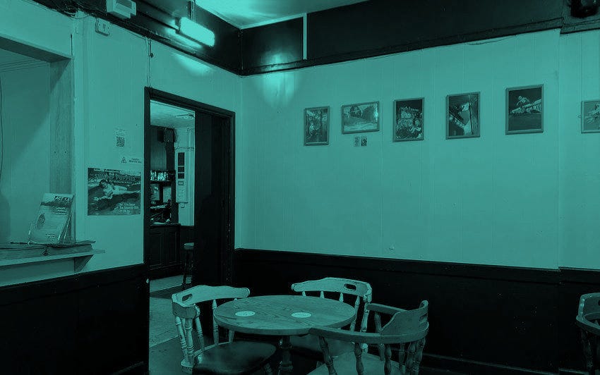 The interior of an East Bristol pub with white walls, wooden furniture, and framed art.