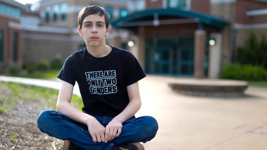 Liam Morrison sitting cross-legged on the ground with tshirt "There are only two genders" Liam Morrison sitting cross-legged on the ground with tshirt "There are only two genders"