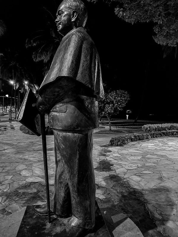 Monochrome photo of Prince Jonah Kuhio statue in waikiki by Kuhio Beach at night. 