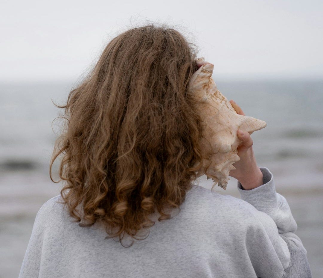 a woman holding a seashell up to her face