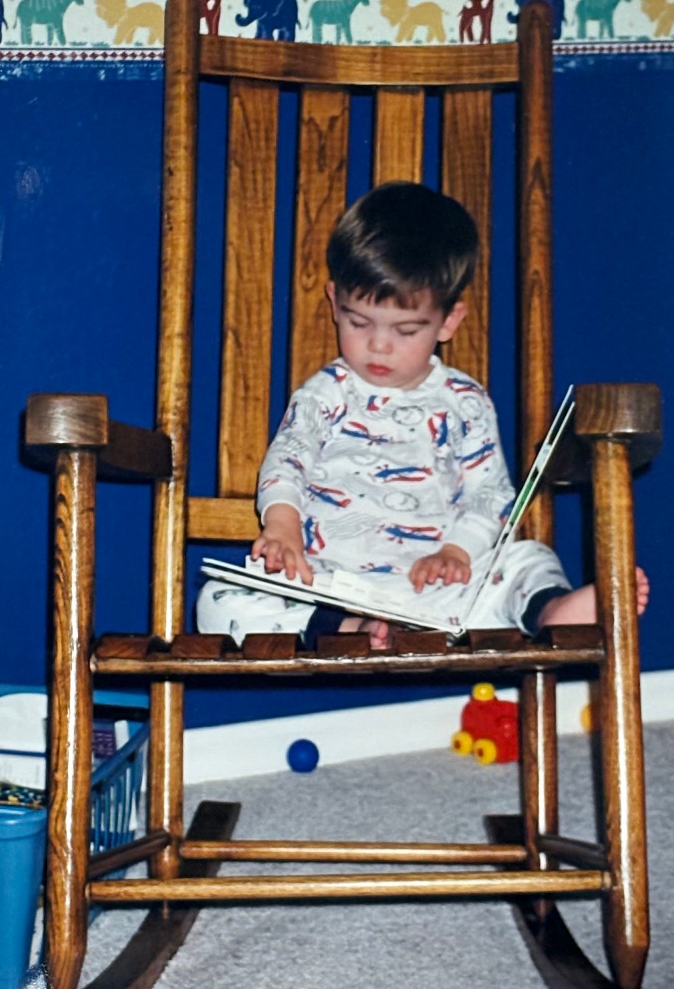 A little boy in a rocking chair reading a book