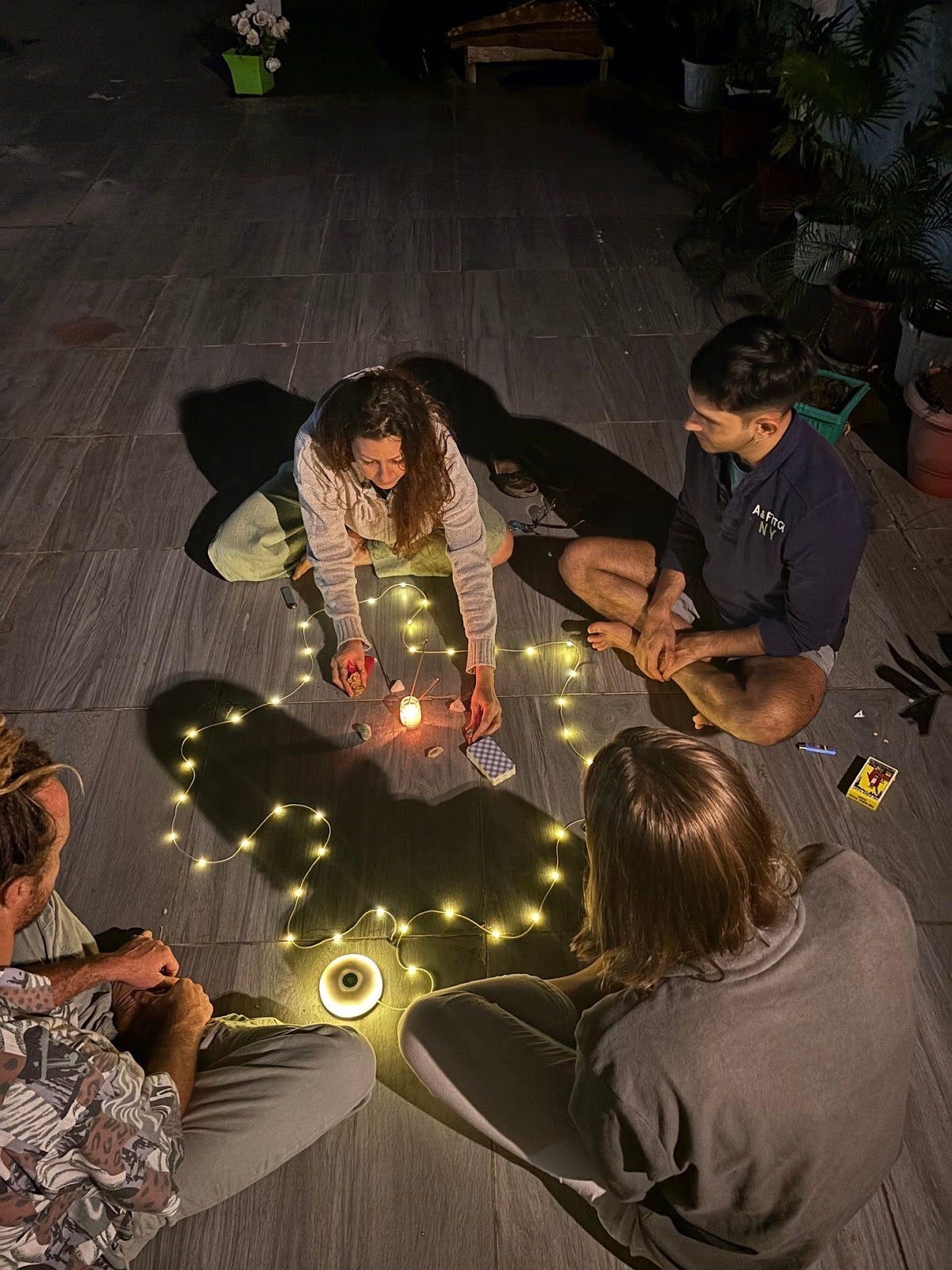 A group of people sitting on the floor with a candle in the middle
Description automatically generated A group of people sitting on the floor with a candle in the middle
Description automatically generated
