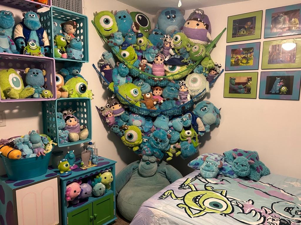 A bedroom decorated with various Monsters Inc. merchandise including plush toys and framed pictures.