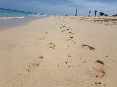 A wooden pier stretching into bright turquoise water, with small waves rolling toward the shore under a clear sky.