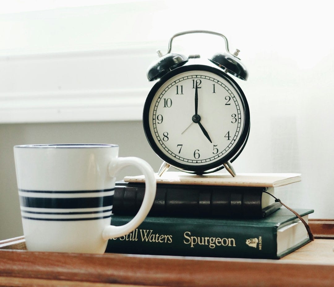 white ceramic mug beside white and black analog alarm clock white ceramic mug beside white and black analog alarm clock