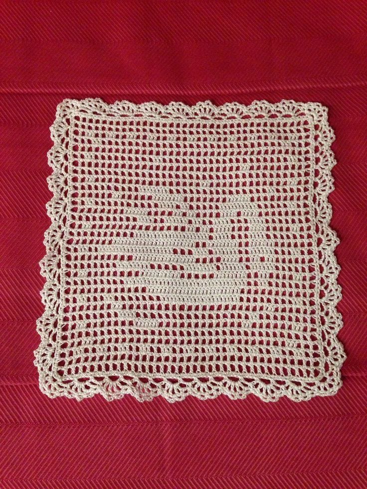 This may contain: a white crochet doily on a red cloth with the word love written across it