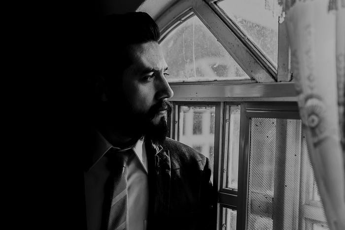 Man looking out a window in contemplation. Man looking out a window in contemplation.