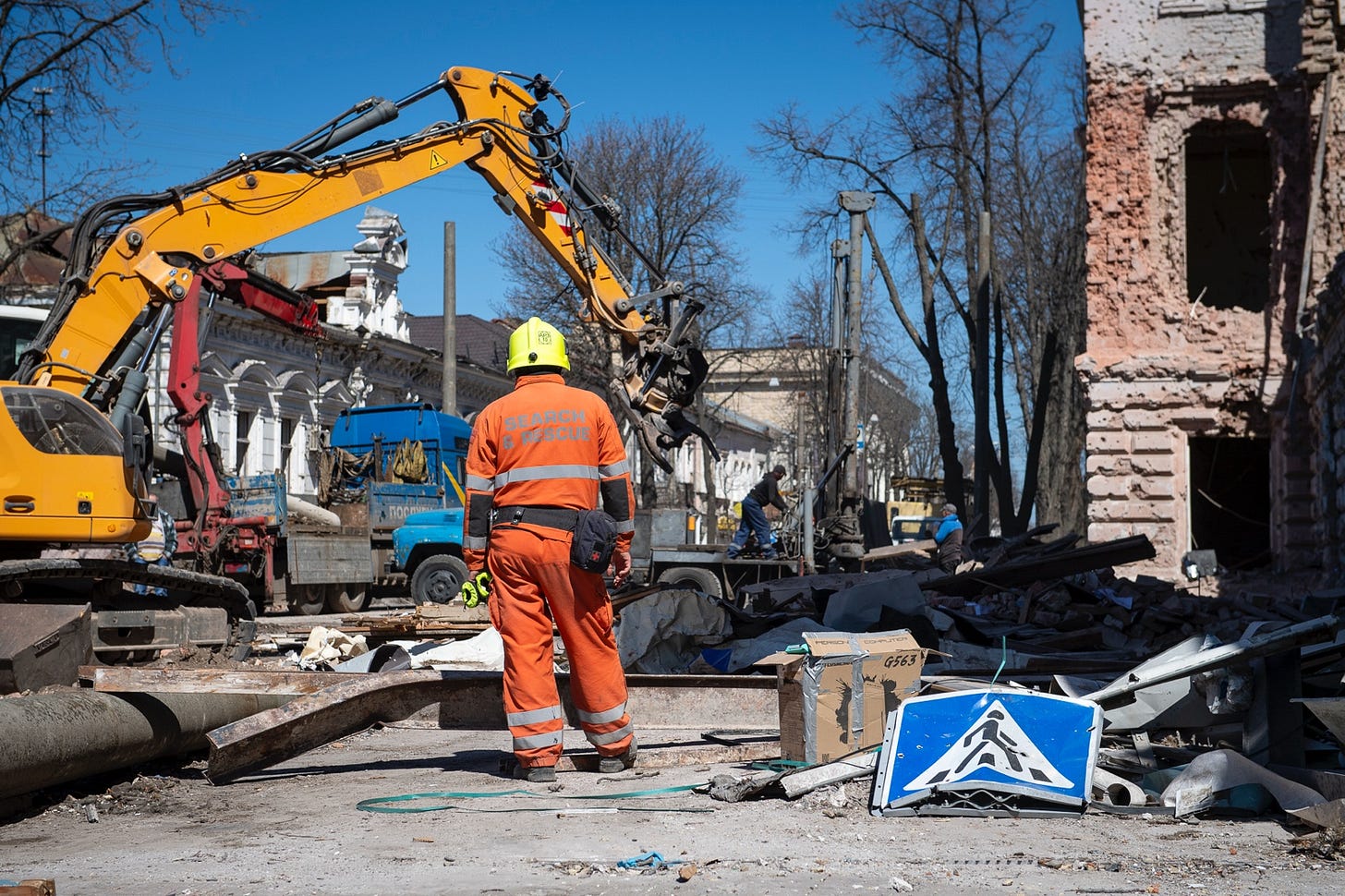 A person in orange overalls and a yellow helmet standing in front of a construction site

AI-generated content may be incorrect.
