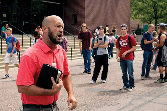 Street preacher Ron Underwood yells back and forth with a growing circle of students surrounding him in near the Plaza Building Aug. 27. Photo by Justin David Tate • jtate15@msudenver.edu