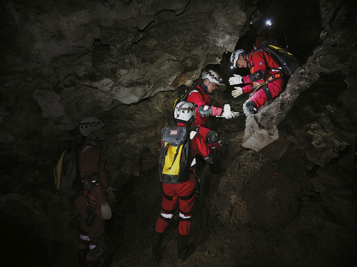 A group of five taikonauts, including Gui Haichao (sat top right) and Li Guangsu (holding the sample), while carrying a sample upward through the cave in December 2025.