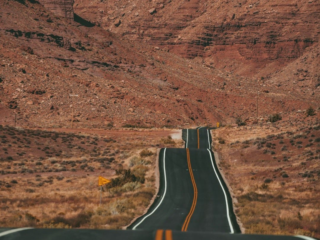 white car on road near brown rock formation during daytime